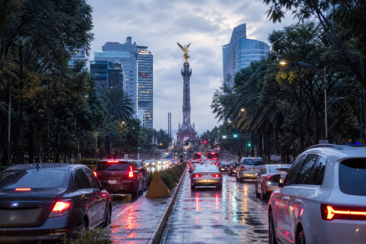 Avenida de la Ciudad de México con tráfico matutino, pavimento mojado y cielo nublado tras la lluvia.