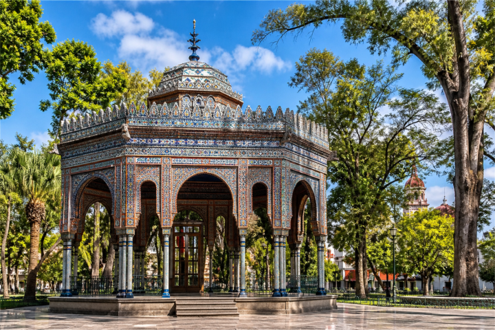 Kiosco morisco con azulejos de colores en un parque arbolado de México.