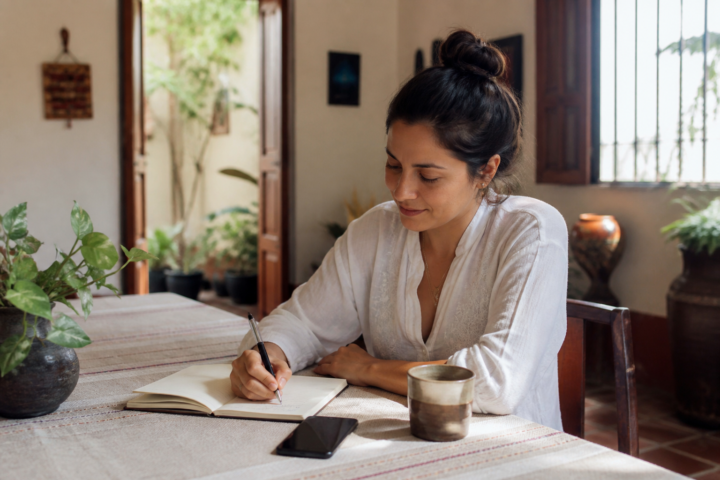 Mesa de trabajo con libreta, teléfono y café para organizar la rutina de la mañana.