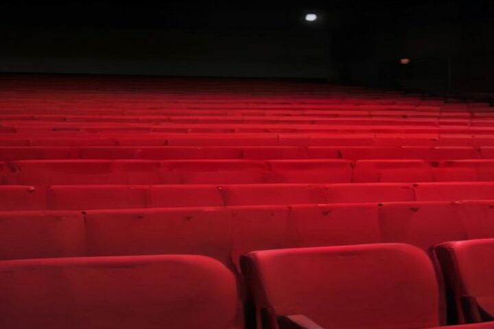 Auditorio vacío con filas de butacas rojas iluminado con luz cálida tenue
