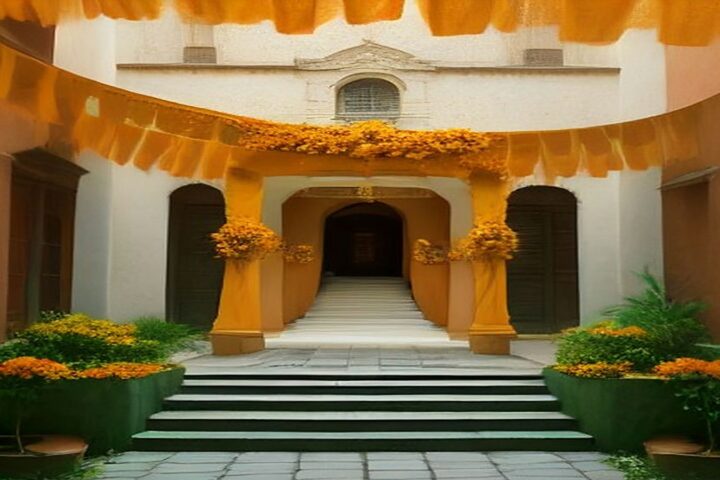 Patio de una casona colonial decorado para Día de Muertos con arcos de flores de cempasúchil, papel picado naranja y escalinata de piedra