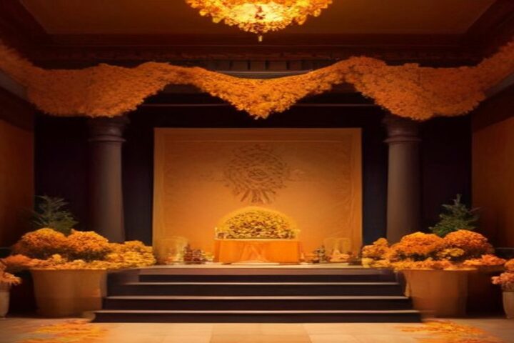 Sala amplia con columnas oscuras y un altar escalonado al fondo, cubierto de flores de cempasúchil y guirnaldas naranjas bajo una luz cálida