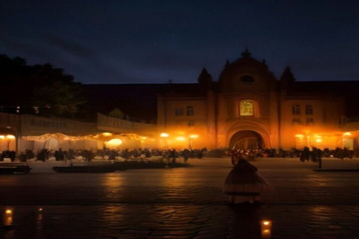 Plaza de un pueblo tradicional de noche durante el Día de Muertos, con la fachada iluminada de una iglesia colonial, velas y guirnaldas de cempasúchil
