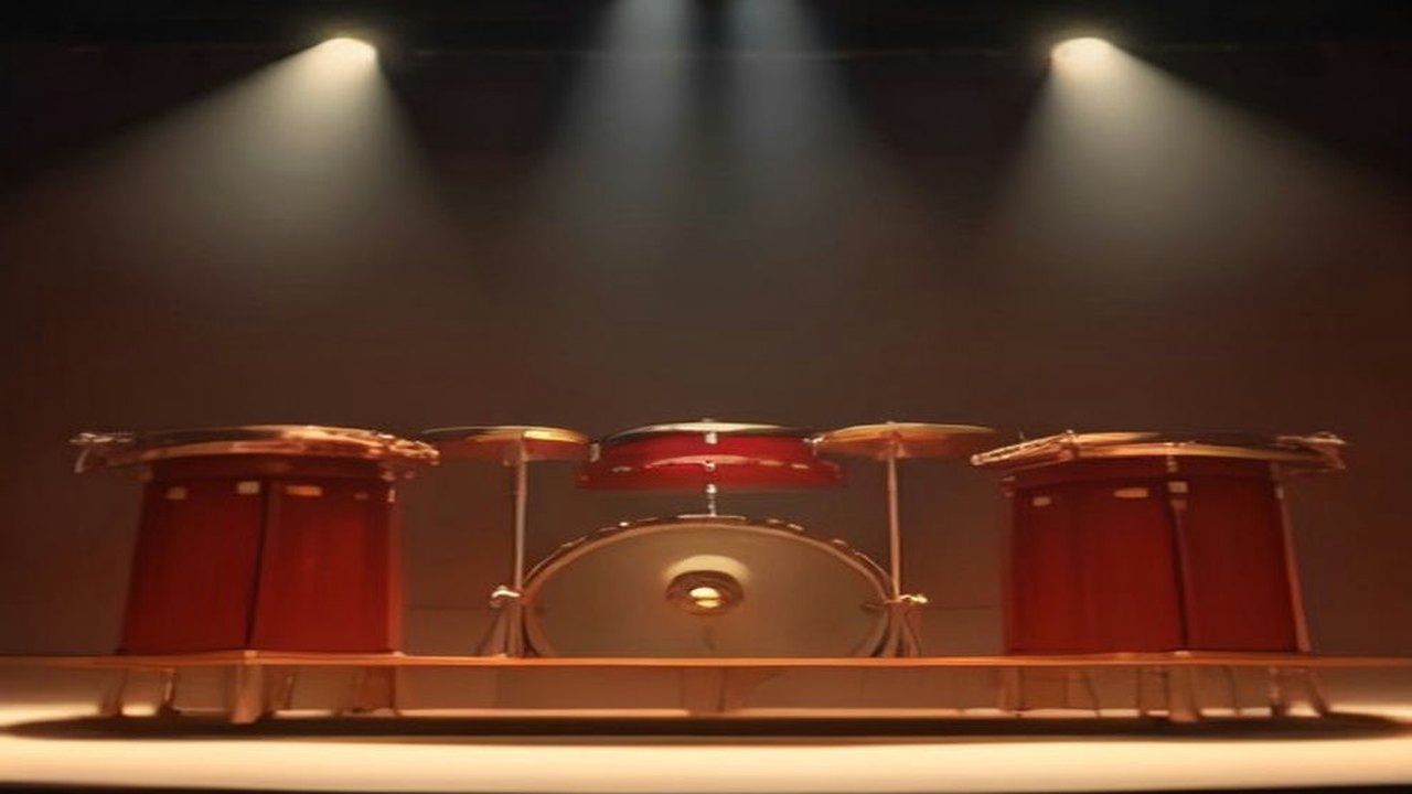 Escenario de concierto con tambores rojos y platillos bajo reflectores de luz cálida en una sala en penumbra