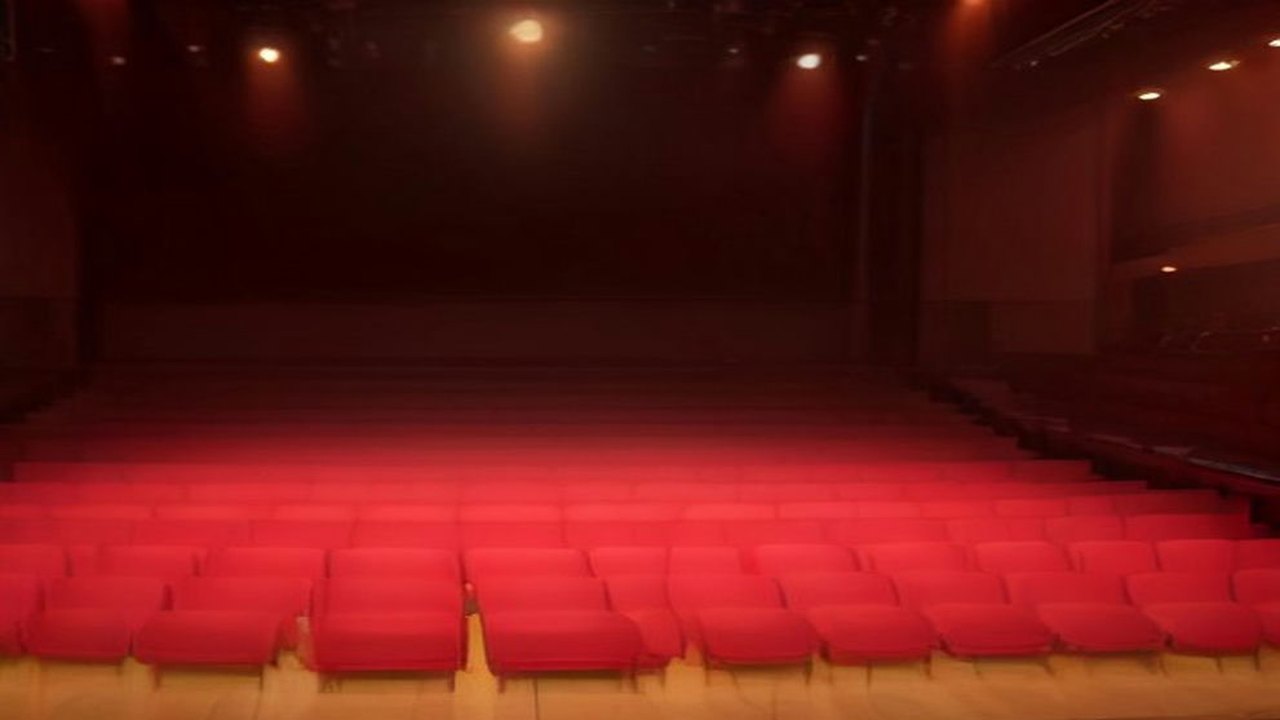 Escenario de una sala de conciertos preparado para mariachi y banda, con trompetas y violines en atriles, un sombrero de charro y luces cálidas