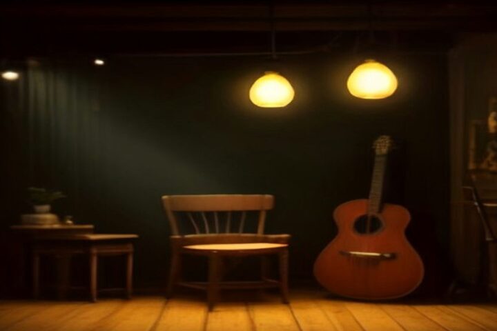 Escenario íntimo con una guitarra recargada junto a una silla de madera y lámparas colgantes de luz cálida