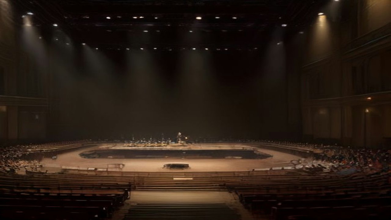 Escenario de una gran sala de conciertos con sillas y atriles de orquesta vacíos, violines y chelos en reposo y un micrófono al centro bajo luz dorada