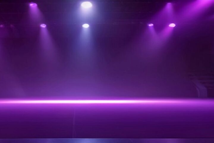 Escenario vacío iluminado por reflectores morados entre la bruma, con la pista despejada y sin público