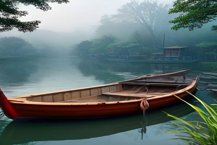 Trajinera de madera de colores amarrada en un canal tranquilo rodeado de árboles y neblina de la mañana